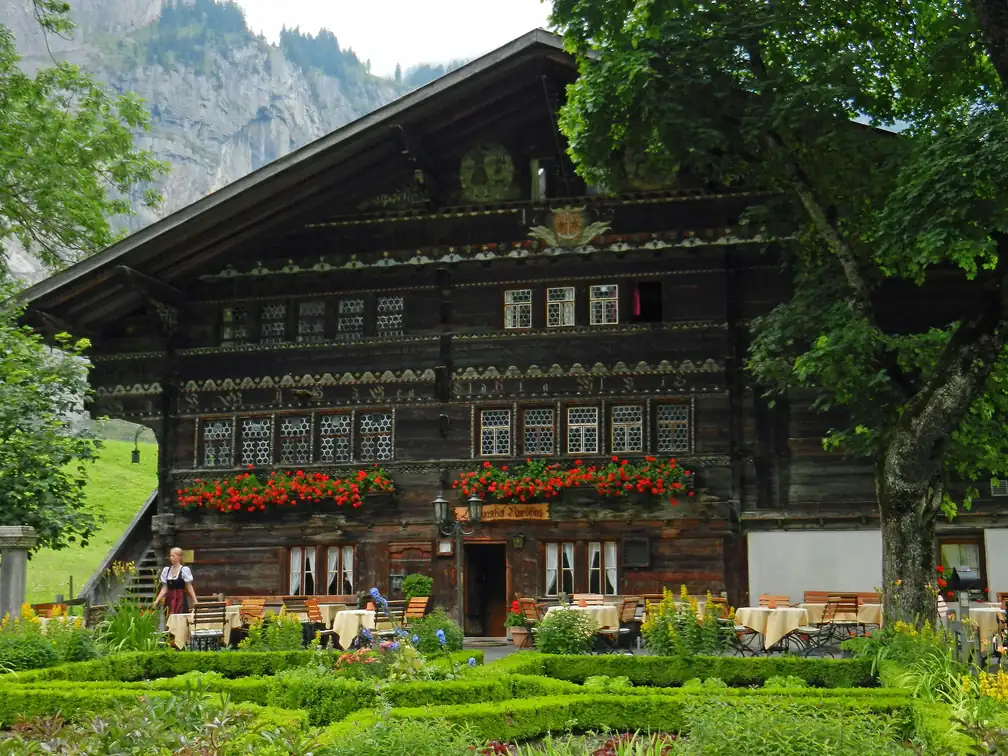 Die ganze Fassade mit Fensterreihen, Geranien und Garten