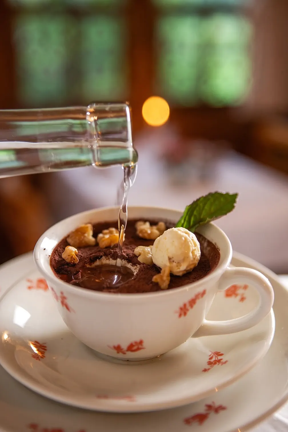 Tasse des Hauses mit Glace und Nüssen, aus einer Flasche wird eingeschenkt