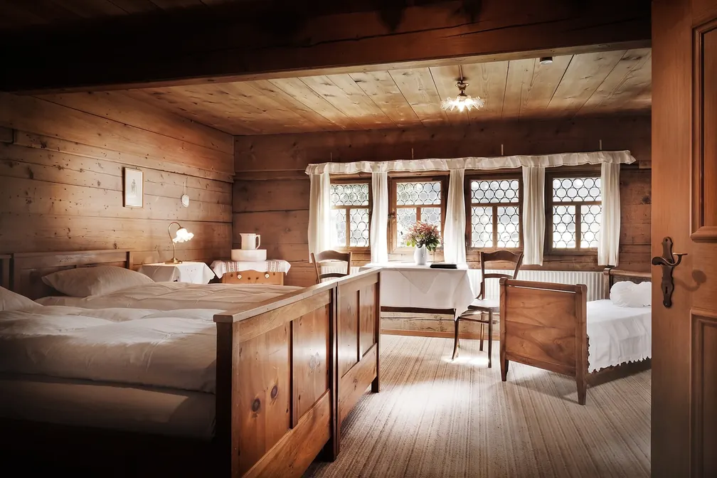 Zimmer mit Holzbetten und Fensterreihe
